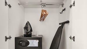 Un mueble compacto con estante plegable para planchar, un electrodoméstico pequeño y una percha.