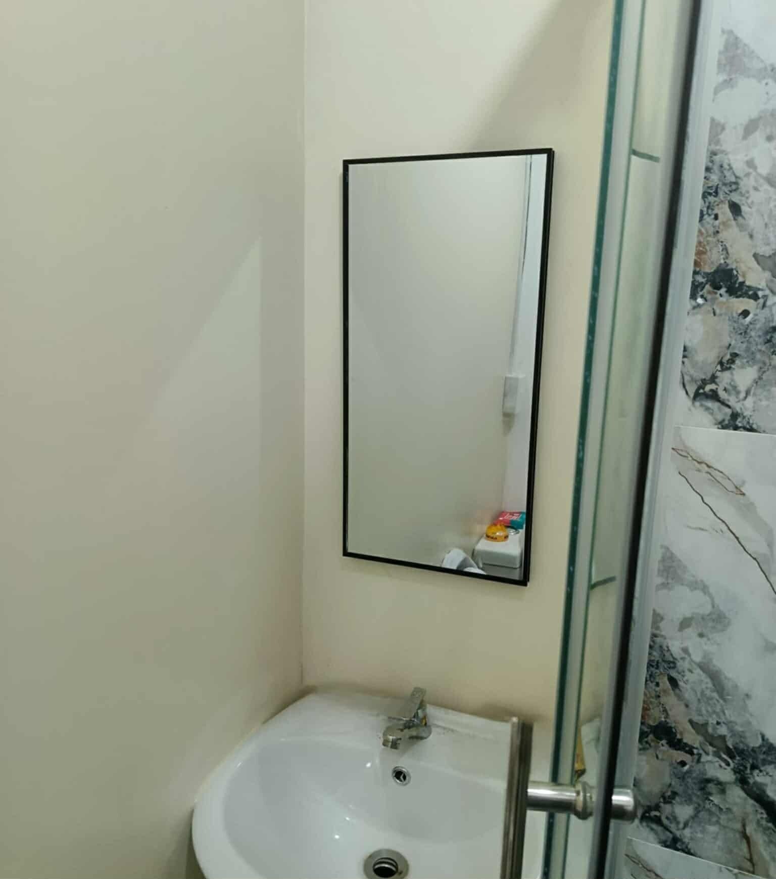 A bathroom with a white sink, a mirror, and a glass shower enclosure.