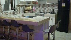 A modern kitchen with a central island, bar stools, a sink, and a stove. - Entire rental unit - bright space and a magnificent overlooking view of area. (San Jose del Monte)