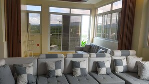 A modern living room with a sectional sofa, large windows, and a view of the outdoors. - Entire rental unit - bright space and a magnificent overlooking view of area. (San Jose del Monte)