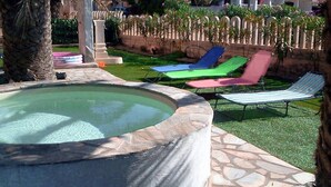 A swimming pool with lounge chairs, a stone deck, and a fence with plants. - 150 Meters From the Sea, 2 Swimming Pools (Valledoria)