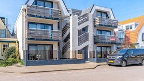 Un immeuble moderne à plusieurs étages, doté de balcons, avec une enseigne bien visible indiquant « ANNA », et un fourgon garé devant.