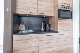 A modern kitchen with wooden cabinets, a stainless steel sink, and an oven.