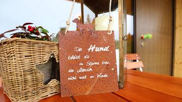 Ein Korbboden mit einem deutschen Schild, einer Kerze und einem Spielzeughund auf einem Holztisch.