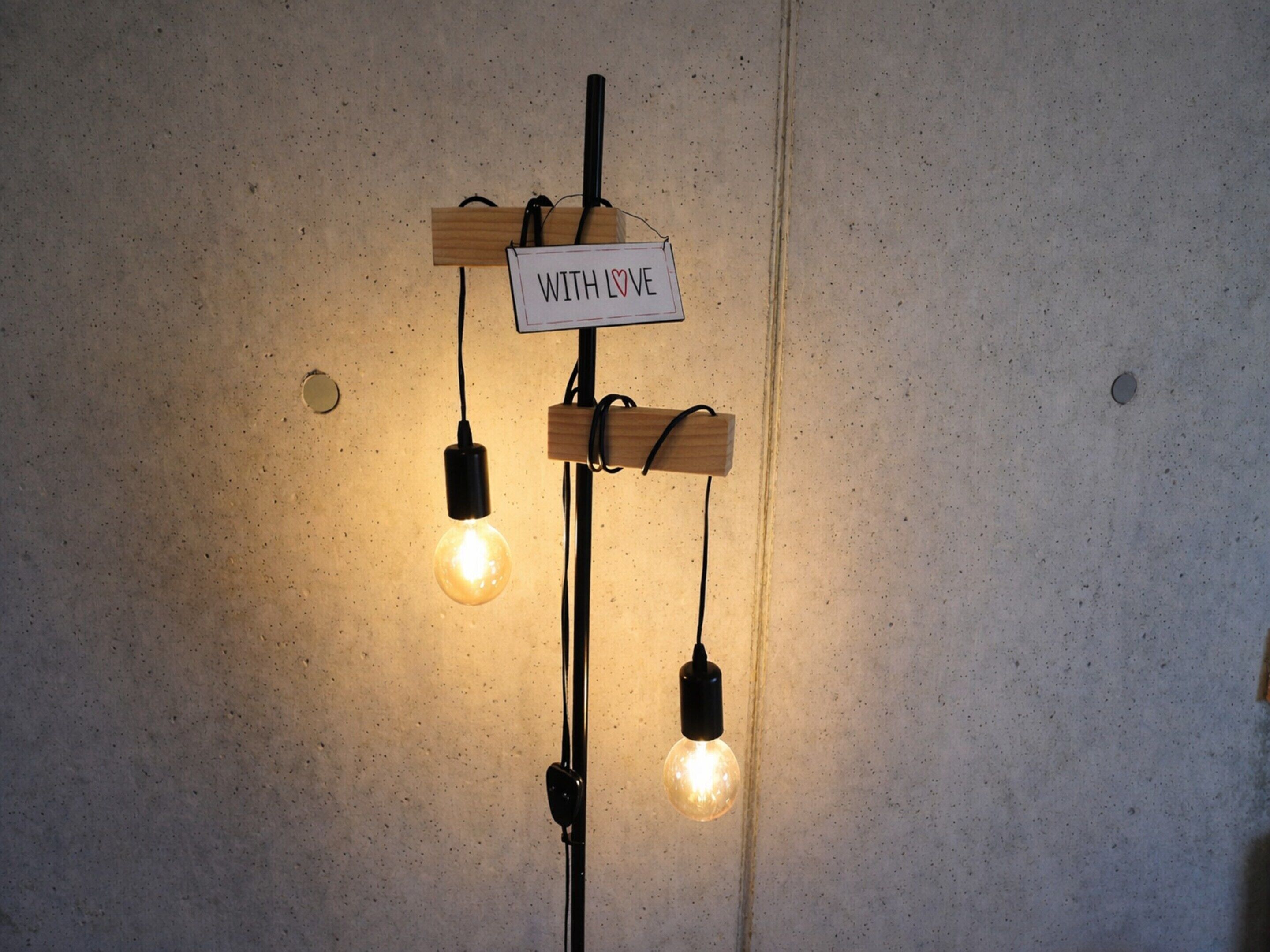 A wall-mounted light fixture with three bulbs and a sign that reads "WITH LOVE".