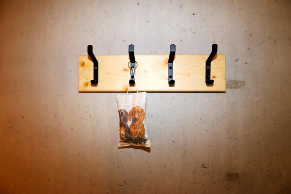 A wooden wall-mounted rack with three hooks and a small bag hanging below. - Dog-friendly Holiday Apartment in Bregenzerwald (Sibratsgfaell)