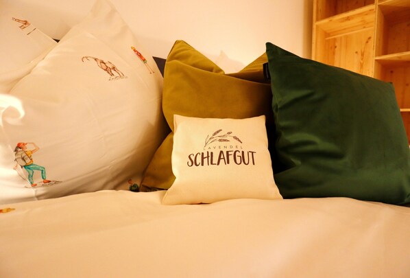 Una cama con varias almohadas, algunas con texto e ilustraciones.