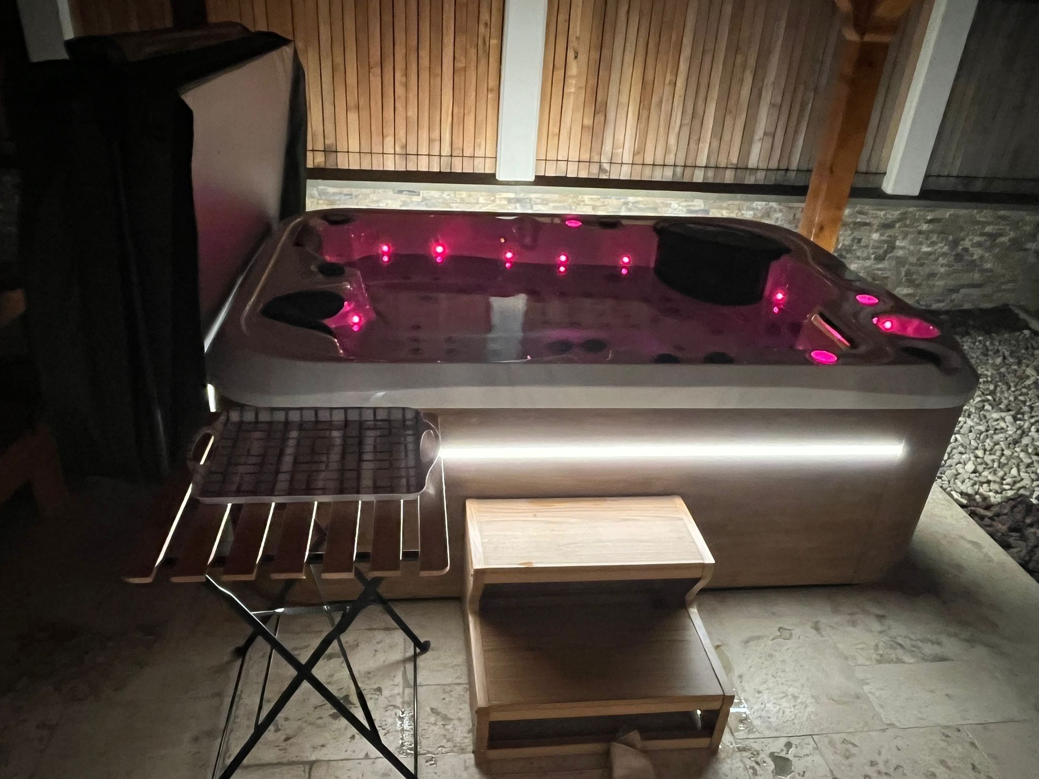 A hot tub with a wooden deck and a small table.