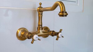 A brass faucet with hot and cold handles on a white wall. - City Panorama Studio by ΜΡS (Athens)