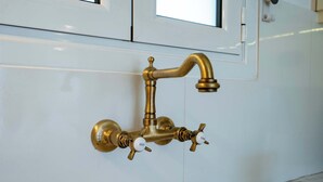 A brass faucet mounted on a white tiled wall. - City Panorama Studio by ΜΡS (Athens)