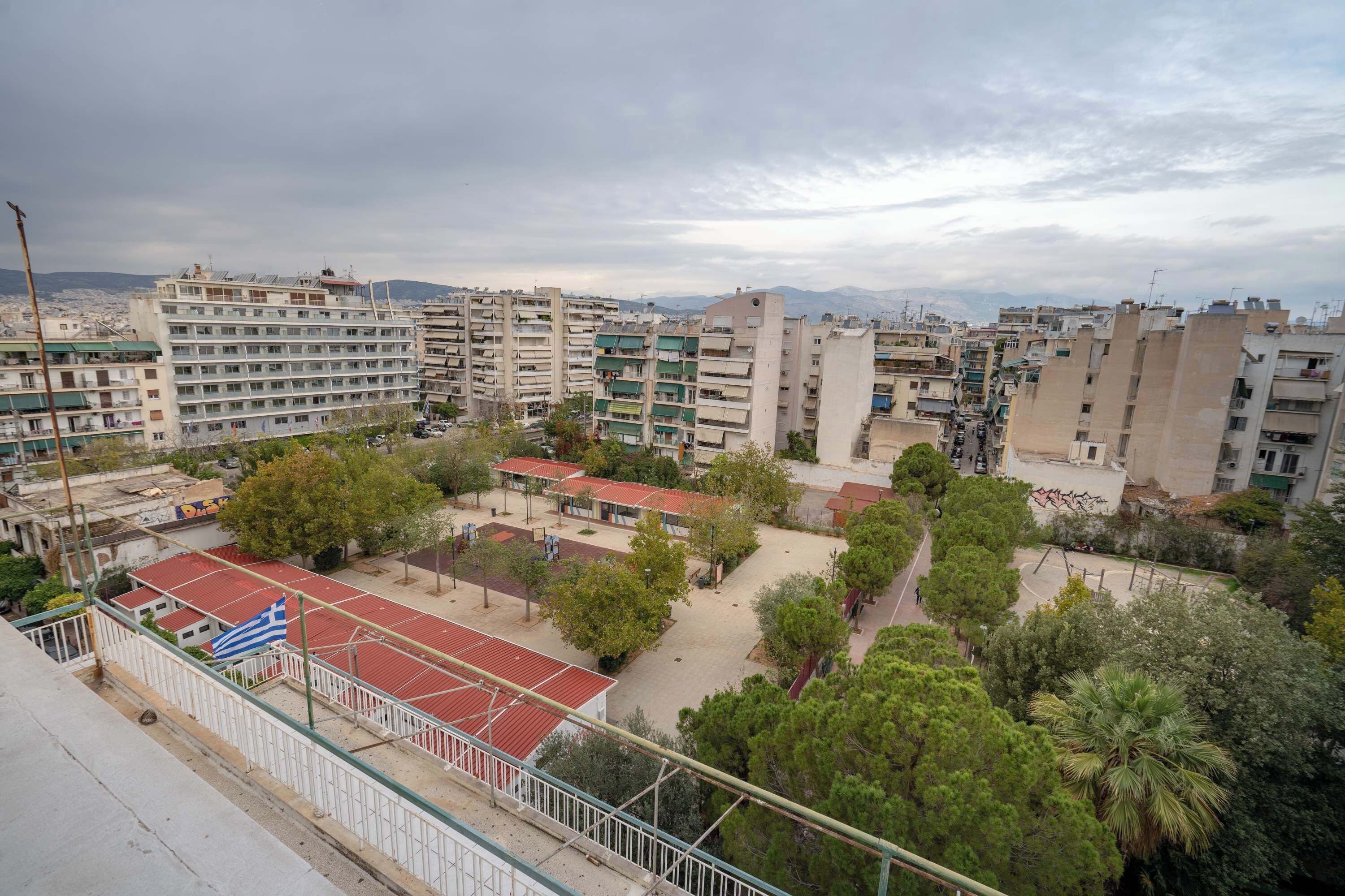 Un quartier résidentiel comprenant plusieurs immeubles d’appartements, un terrain de basket et un mât portant un drapeau.