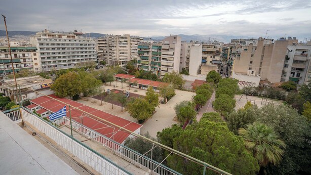 A residential area with multiple apartment buildings, a basketball court, and a flag. - City Panorama Studio by ΜΡS (Athens)