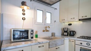 A kitchen with white cabinets, a microwave, a sink, a stove, and a coffee maker. - City Panorama Studio by ΜΡS (Athens)