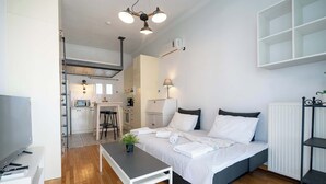 A modern hotel room with a bed, bedside table, and a desk with a chair. There is a kitchenette in the background. - City Panorama Studio by ΜΡS (Athens)