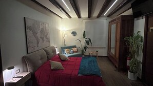 A bedroom with a bed, a nightstand, a lamp, a map on the wall, a dresser, and a plant. - IRIDE HOME _ Wellness & Relaxation (Bergamo)