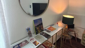 A room with a round mirror, a table with books, a lamp, and a chair. - IRIDE HOME _ Wellness & Relaxation (Bergamo)