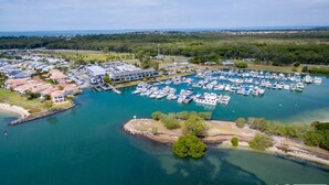 En vy från ovan över en småbåtshamn med många båtar förtöjda, omgiven av bostadshus och grönområden.