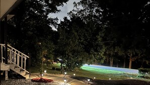 A landscaped area with gravel paths, trees, and outdoor lighting. - Luxurious 5-bedroom house with Game Room in Stone Mountain (Stone Mountain)
