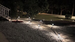 A pathway with evenly spaced street lamps, a grassy area, and trees in the background. - Luxurious 5-bedroom house with Game Room in Stone Mountain (Stone Mountain)