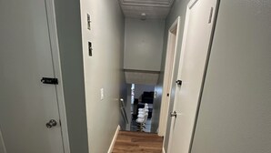 A narrow hallway with wooden flooring, white walls, and a ceiling fan with three light bulbs. - Luxurious 5-bedroom house with Game Room in Stone Mountain (Stone Mountain)