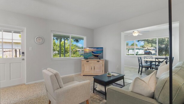 A living room with a television, a sofa, a coffee table, and a dining area with a table and chairs. - Cozy Cottage Minutes from the Beach (Sarasota)
