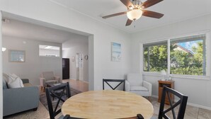 A dining area with a round wooden table, black chairs, and a ceiling fan. - Cozy Cottage Minutes from the Beach (Sarasota)