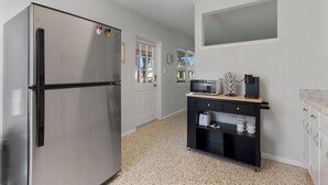 A compact kitchen with a stainless steel refrigerator, a microwave, a coffee maker, and a small black cabinet. - Cozy Cottage Minutes from the Beach (Sarasota)