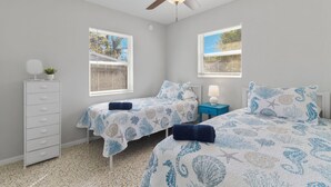 A bedroom with two beds, a ceiling fan, a dresser, and a nightstand with a lamp. - Cozy Cottage Minutes from the Beach (Sarasota)