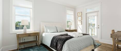 A bedroom with a bed, bedside tables, a desk, and a chair.