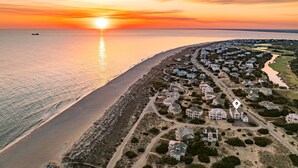 A coastal residential area with houses, a beach, and a sunset. - Steps to the Beach: 6BR Gem / Ocean Views / BHI + Shoals Club / 2 Carts (Bald Head Island)