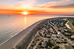 A coastal residential area with houses, a beach, and a sunset. - Steps to the Beach: 6BR Gem / Ocean Views / BHI + Shoals Club / 2 Carts (Bald Head Island)