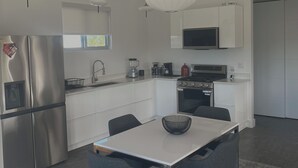 Une cuisine moderne dotée d’appareils électroménagers en acier inoxydable, d’une table à manger avec des chaises et d’un éclairage suspendu.