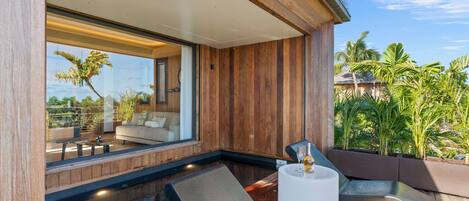 A modern outdoor pool area with wooden decking, lounge chairs, and a glass enclosure offering a view of the surrounding landscape.
