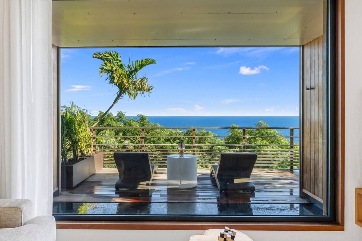 A balcony with a view of the ocean, two lounge chairs, and a small table.