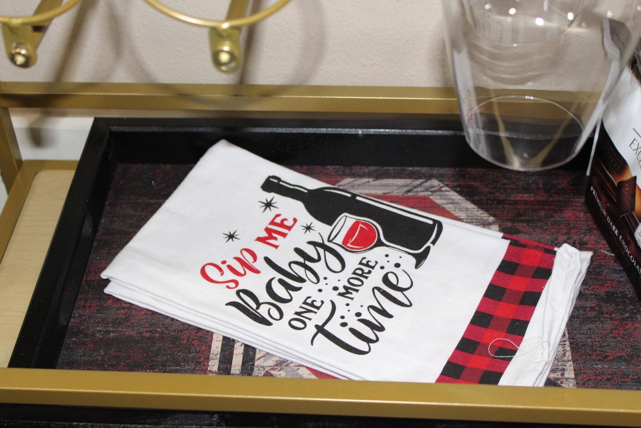 A tray with a napkin featuring a baby bottle and wine glass design, and a glass container in the background.