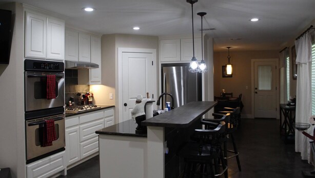 A modern kitchen with white cabinetry, stainless steel appliances, and a central island with bar stools.