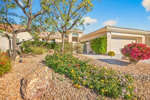A residential area with a house, a driveway, and a garden with various plants and flowers. - NEW! Beautiful, Sun City 2bd 2ba 1624sf home, amenities, golf cart & clubs 55+ (Palm Desert)