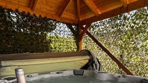 Un bain à remous avec une bouteille de vin et deux verres sur une terrasse en bois.