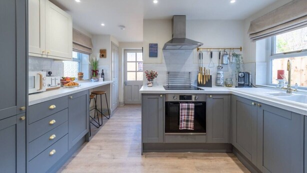 Une cuisine moderne avec des meubles gris, un four encastré et une fenêtre offrant une belle vue.