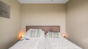 Ein Doppelbett mit weißer Bettwäsche, grün gestreiften Kissen, einem Holzkopfende und Nachttischlampen.
