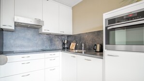Eine moderne Küche mit weißen Schränken, einem Edelstahlbackofen und einer Kaffeemaschine.