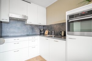Eine moderne Küche mit weißen Schränken, einem Edelstahlbackofen und einer Kaffeemaschine.