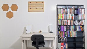 Um espaço de trabalho com escrivaninha, cadeira, estante e formas hexagonais decorativas na parede.