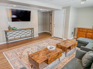 Un salon comprenant une table basse en bois, un canapé, un téléviseur et une console sur laquelle sont disposés des objets décoratifs.