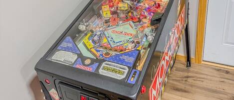 Una máquina de pinball con temática de Monopoly, que incluye un monitor mostrando el juego y varios elementos del juego en su interior.