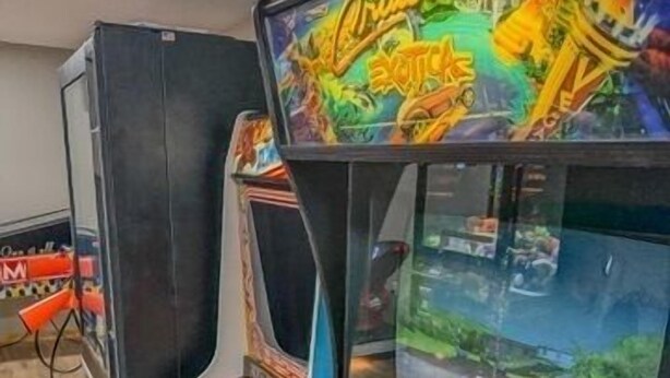 A vintage arcade machine with a steering wheel and a screen displaying a racing game.