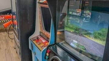 Une borne d’arcade ancienne, dotée d’un volant et d’un écran affichant un jeu de course.