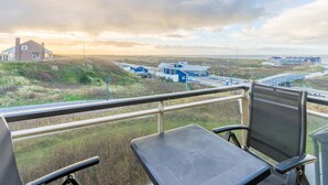 Un balcon offrant une vue sur un paysage côtier, avec des maisons et un pont.