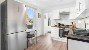 Una cocina moderna con electrodomésticos de acero inoxidable, un comedor con una silla y vistas al exterior.