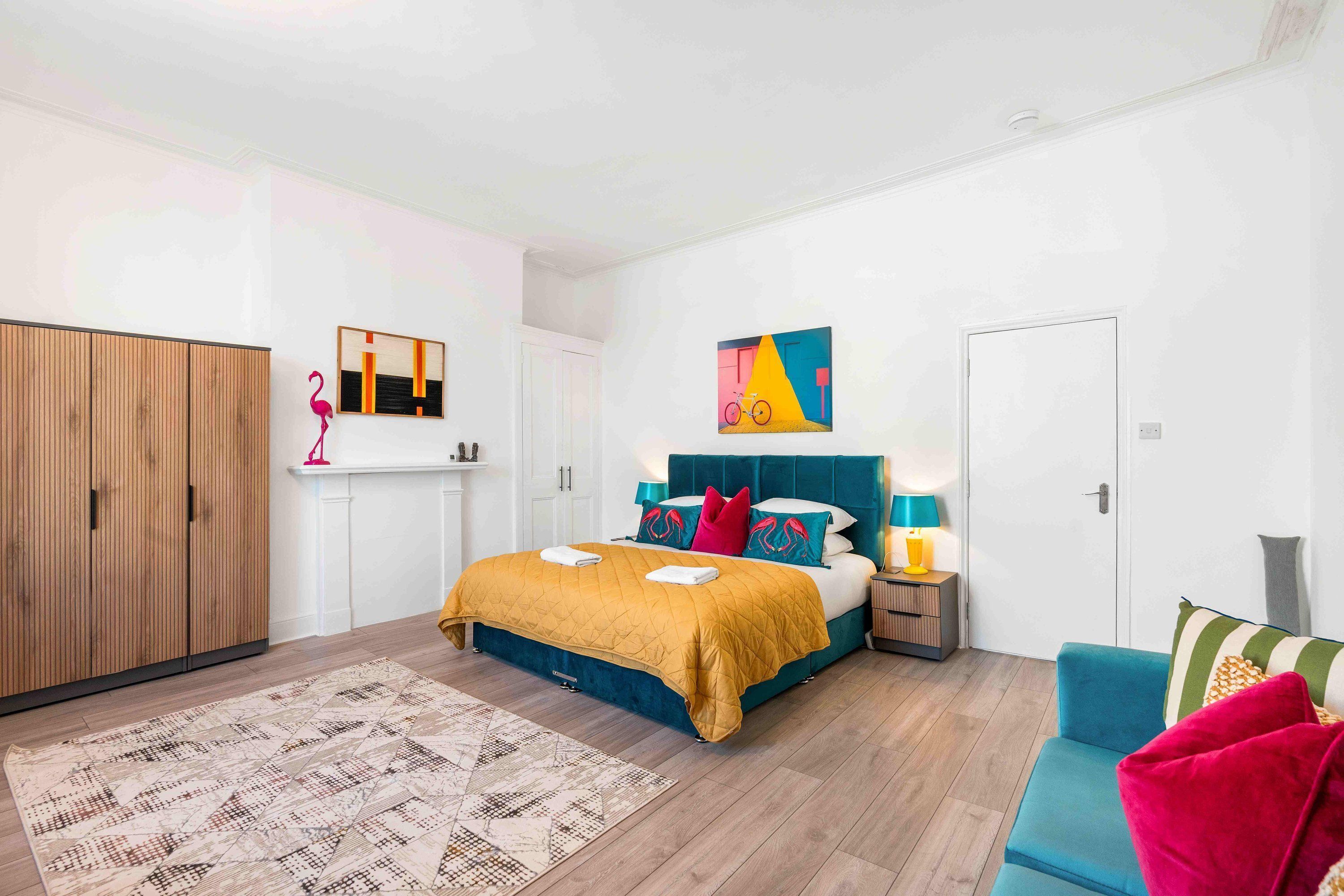 Une chambre à coucher comprenant un lit, une armoire, une table de chevet, une lampe et un canapé.